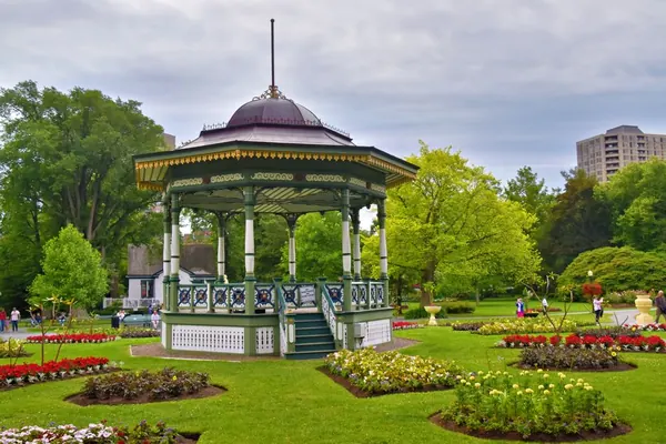 Victorian park bandstand among flower beds and mature trees