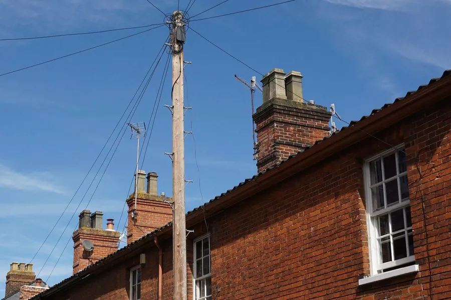 Tall brick chimney stack with lead flashing against a clear summer sky