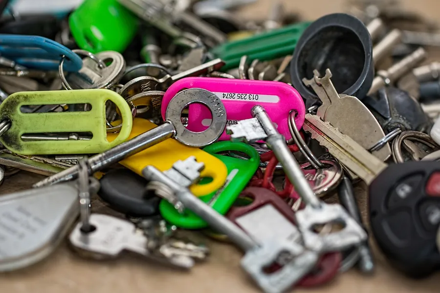 A heap of house keys with coloured plastic key covers and fobs
