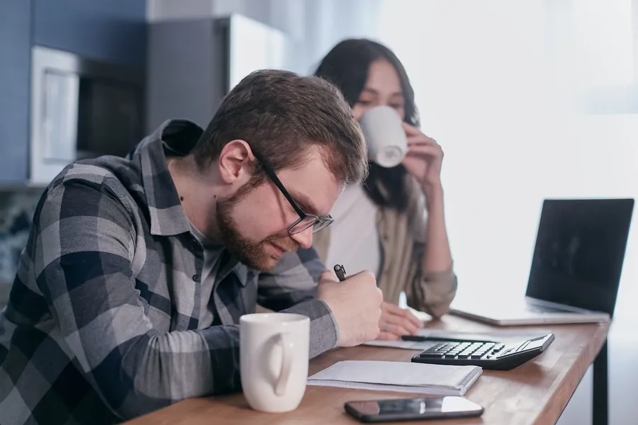 Couple working through building quotes with a calculator at a kitchen table