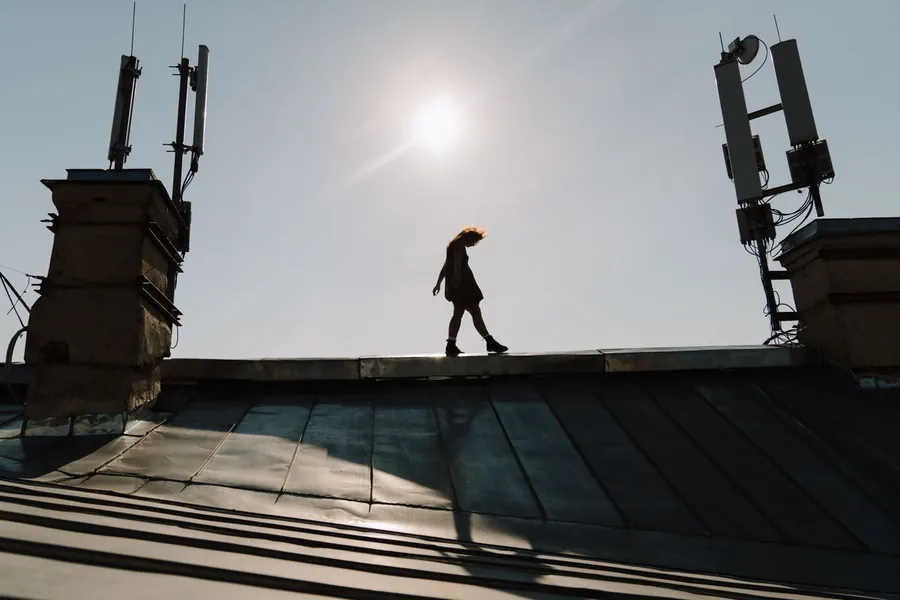 Figure silhouetted on a flat roof under a fierce midday sun