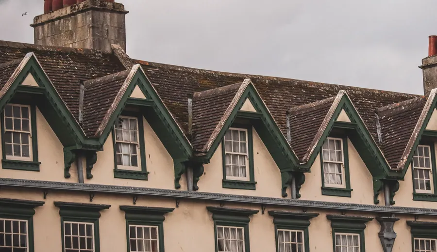 A run of front-facing gabled dormers along a terrace roofline, the kind of roof enlargement Class B will not cover on an elevation that fronts a highway