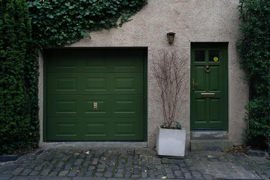 Brick garage with a flat roof beside a house on a cobbled British street