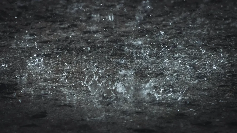 Heavy rain splashing off a dark, flat, wet surface