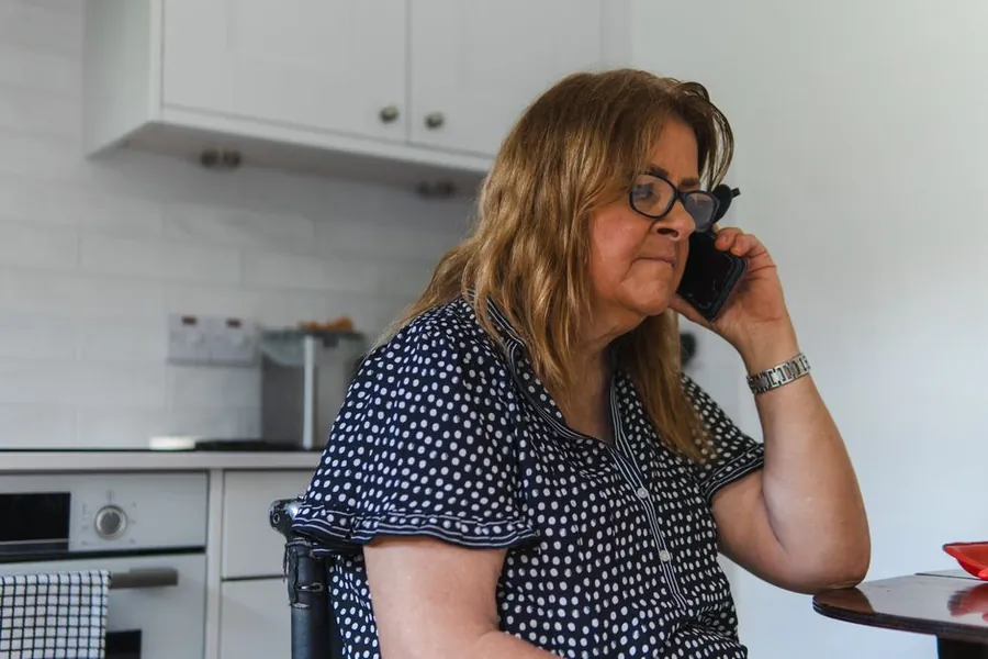 Homeowner at her kitchen table on the phone to her insurer about a roof leak