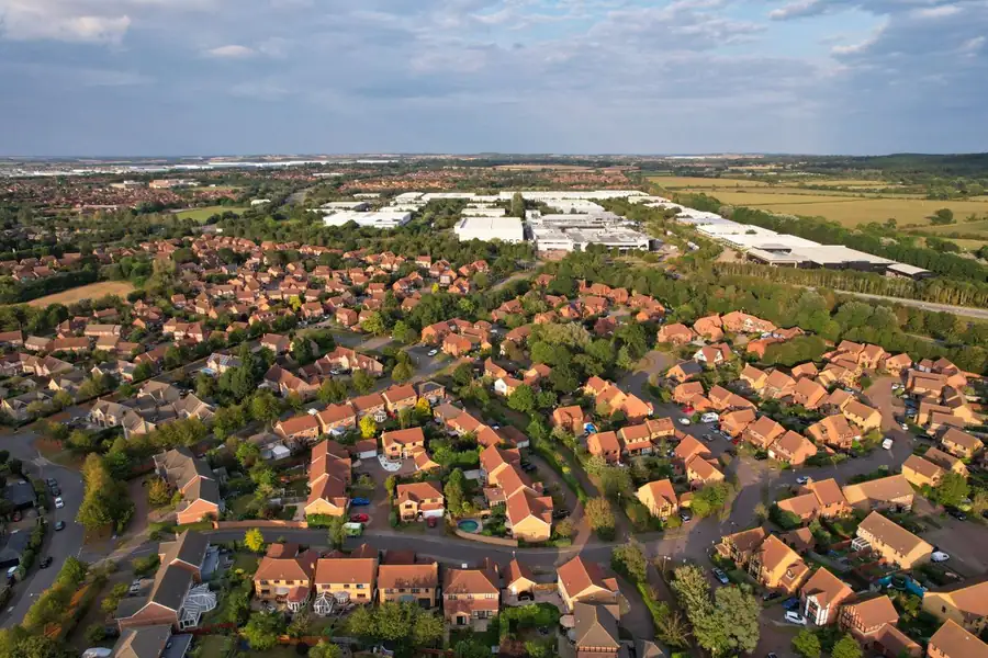 Aerial view of an interwar housing estate with rows of matching tiled roofs in bright sunshine