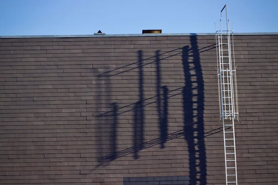 A ladder casting its shadow on a brick wall, the simple access that keeps many Feltham and Hanworth roof repairs affordable