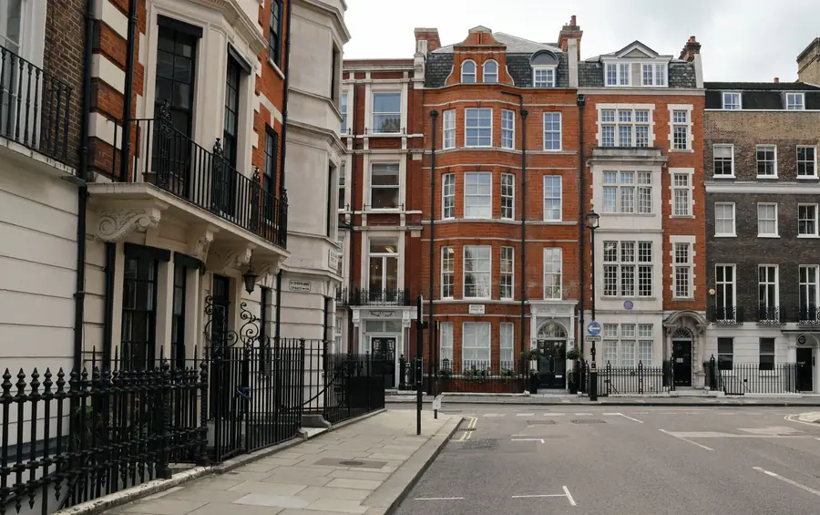 Listed red brick and stucco buildings with mansard roofs on a London conservation area street