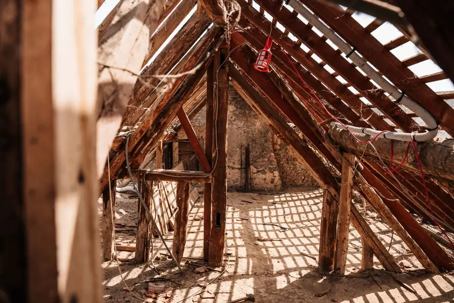 Sunlight through the rafters of a bare roof space showing battens and timbers