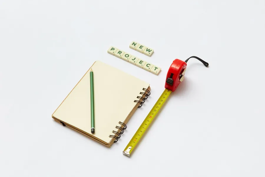 Notebook, pencil and tape measure laid out for measuring up a roof repair or replacement quote