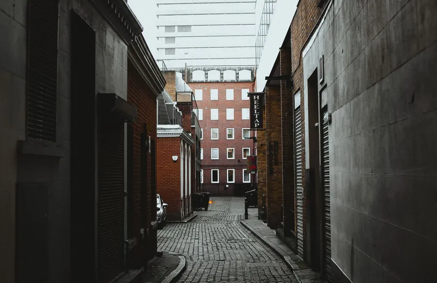 Narrow cobbled back alley running between brick buildings in London