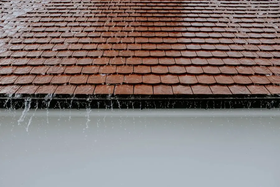 Rainwater pouring off a roof edge during heavy rain on a west London house