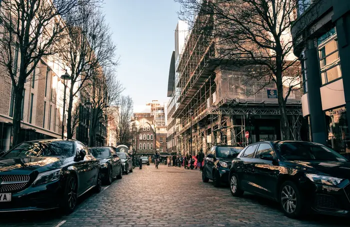 Scaffolding erected along a London street with cars parked either side