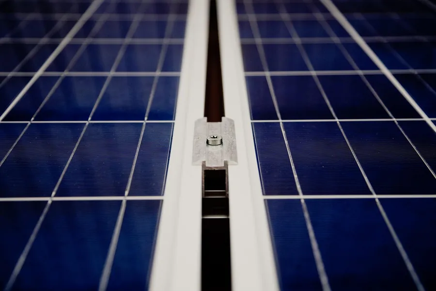 Close-up of two solar panels with the aluminium mounting clamp and gap between them