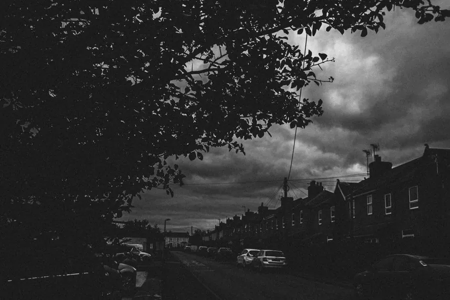 Dark storm clouds building over a street of terraced houses, the weather behind many emergency roof calls in Hounslow