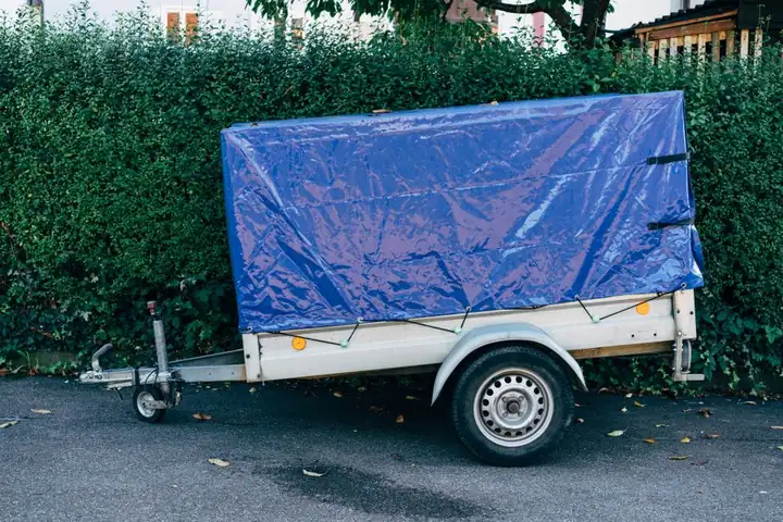 Blue tarpaulin lashed down tightly with rope, the kind of secure fixing an emergency roof make-safe needs