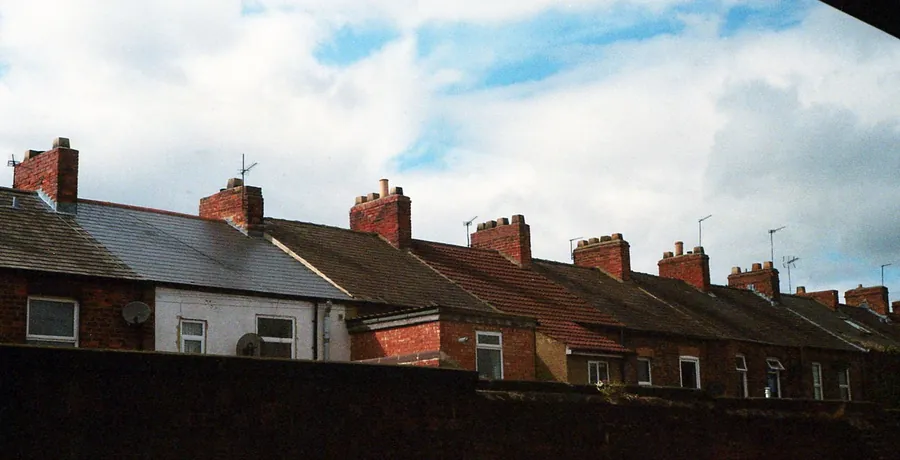 Brick chimney stacks and flashing along a row of British terraced house roofs