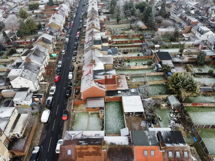 Rear extensions with flat roofs joined to the back walls of terraced houses, seen from above on a frosty morning
