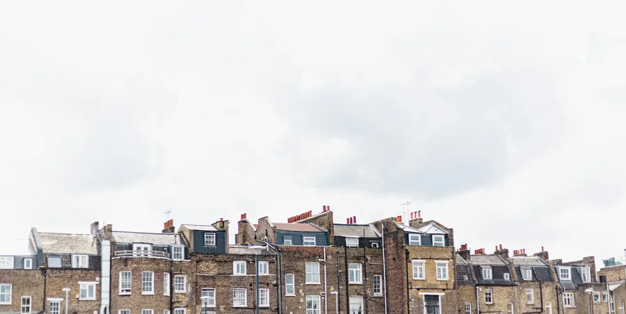 A long run of terraced rooftops with slate coverings, dormers and chimney stacks, like the older streets of Brentford