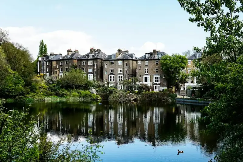 Tall Victorian villas with slate roofs and chimneys reflected in still water, the kind of waterside setting found along Chiswick's riverside conservation areas