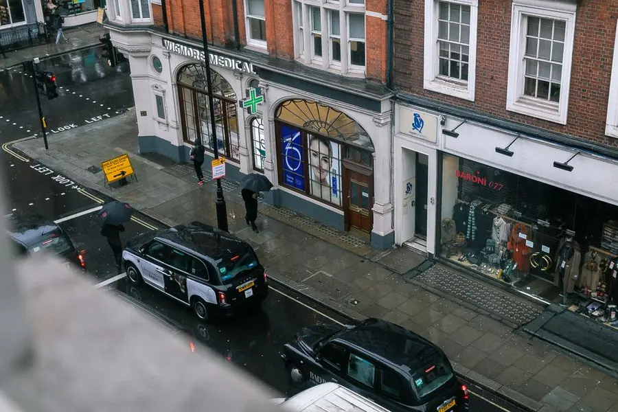 Rain-soaked west London street seen from above, the kind of wet spell that delays a permanent roof repair