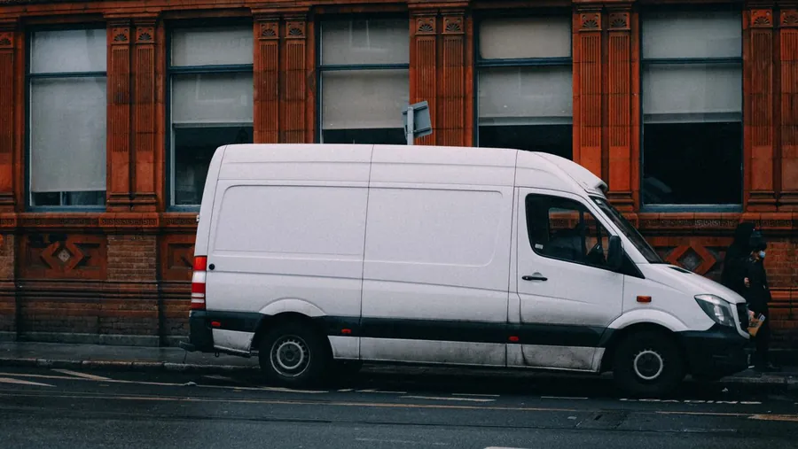 White work van parked on double yellow lines outside a red brick building in London