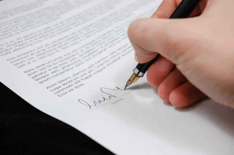 Hand signing a printed document with a fountain pen