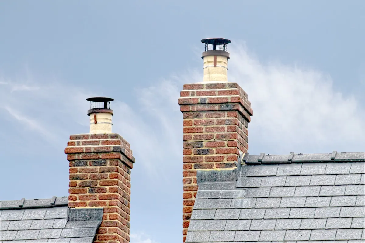 Twin brick chimney stacks with new caps on a slate-roofed west London house