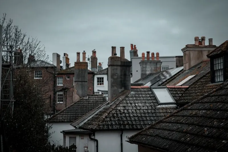 Rows of brick chimney stacks along terraced rooftops in west London