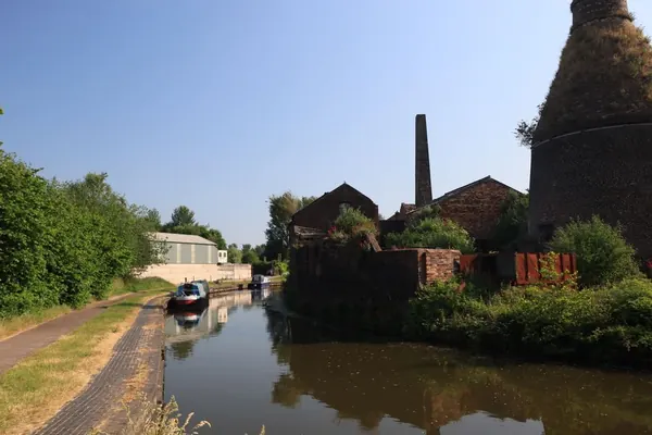 Narrowboat moored on a quiet canal beside old industrial buildings