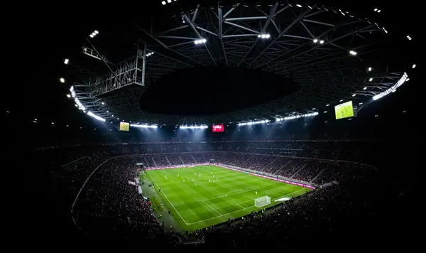Modern football stadium stands under floodlights on a match day