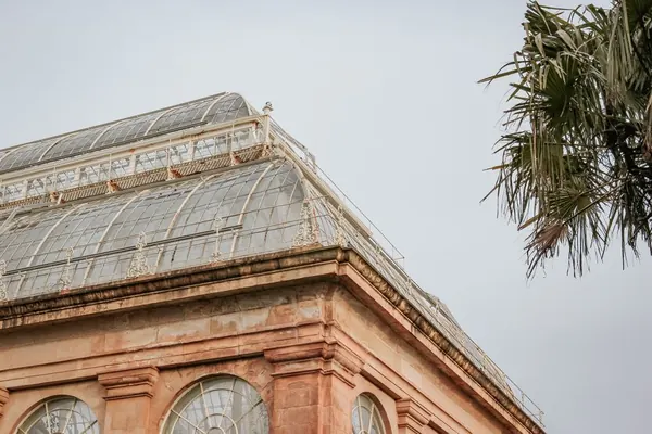 Great curved Victorian glasshouse rising above formal gardens