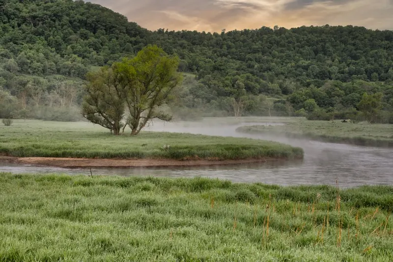 River curving through wooded meadows seen from a hillside