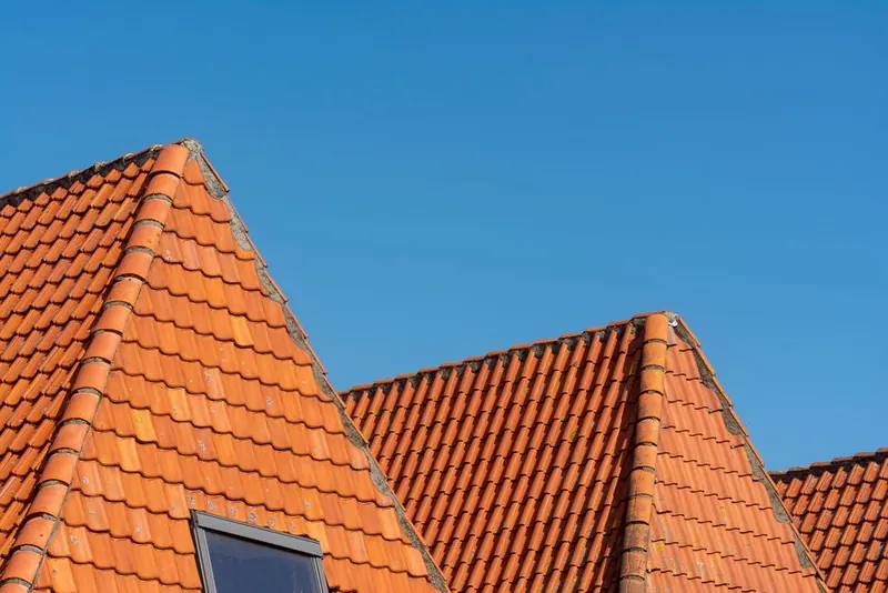 Crisp new clay tiles and rooflight on a freshly re-covered pitched roof