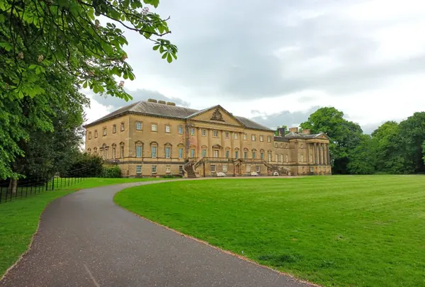Historic stately home seen across sweeping parkland on a bright day