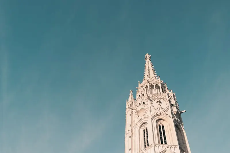 White gothic tower with pinnacles against a blue sky