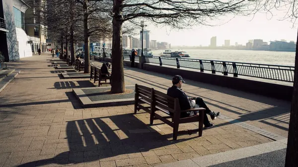 Tree-lined riverside promenade with benches beside the water