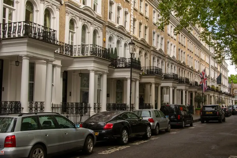 Mature street trees overhanging Victorian terraced houses on a west London avenue